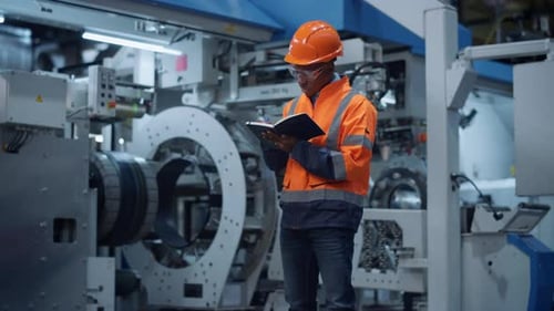 African American Engineer Taking Notes of Project Data at Manufacturing Factory. Professional