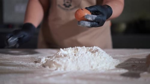 Person Cracking Egg into Mound of Flour