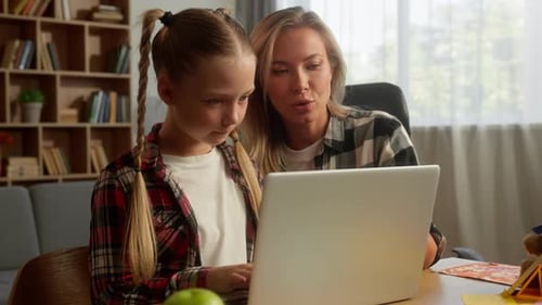 Child Typing on Laptop with Mother at Home