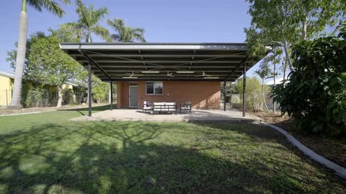 Verandah and patio with chairs, lounge and dining area overlooking grass on a residential property.
