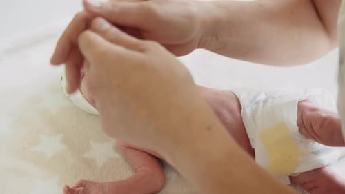 Adult Adjusts Hat of Lying Infant
