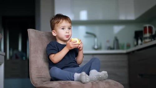 Cute Boy Eating Apple in Bright Kitchen