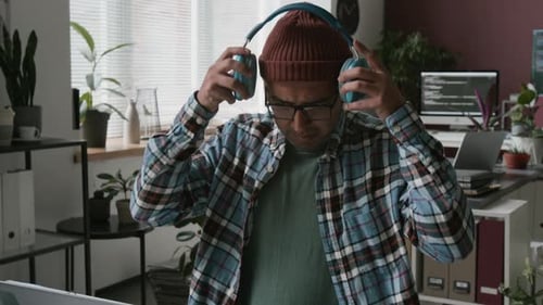 Happy Indian Male Programmer Coding and Enjoying Music in Office