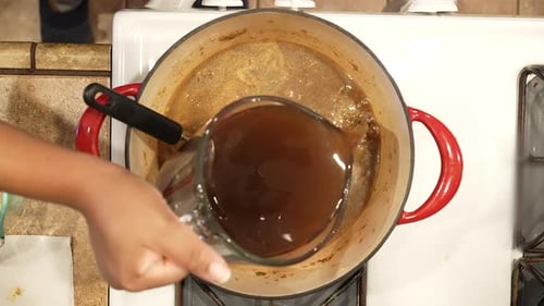 Adding savory broth to a vegan wild rice and mushroom soup - overhead isolated view WILD RICE SERIES