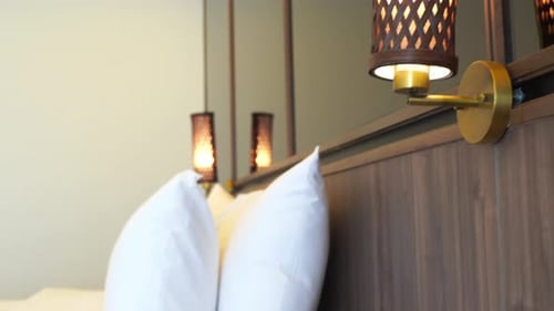 Contemporary tropical interior of a hotel bedroom with mirrors, wooden lamps and headboard over a be