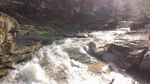Aerial view of a mountain river with beautiful waterfall in the afternoon sunlight