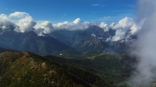 Breathtaking aerial view of green mountains under blue sky with clouds