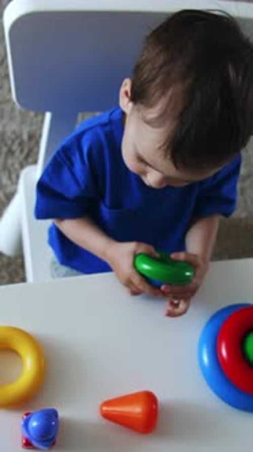 Lindo bebé sonriente sostiene los anillos en sus manos. Niño caucásico montando la pirámide
.