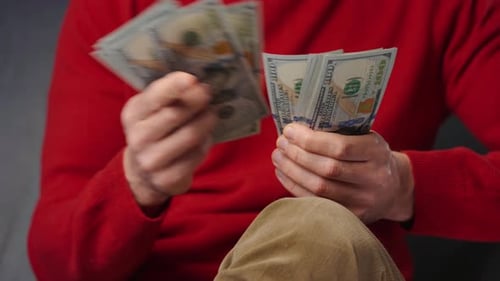 Man Counting Hundred Dollar Bills Indoors