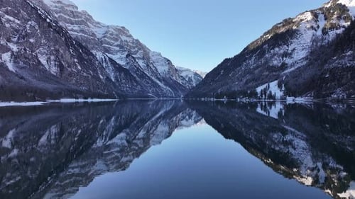 Aerial winter landscape with the snow-covered mountains reflecting in the peaceful lake