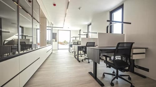 Arcing slider shot of corporate clean office space with back-to-back desk setups