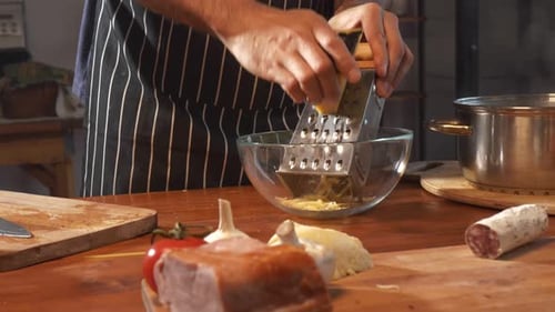 A Man Grates Cheese Against the Backdrop of a Kitchen Interior and Surrounded By a Set of Products