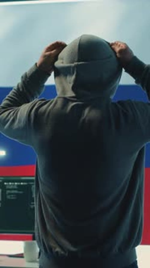 Vidéo verticale Un hacker russe avec une capuche installe la panique par une idée fausse et une manipulation