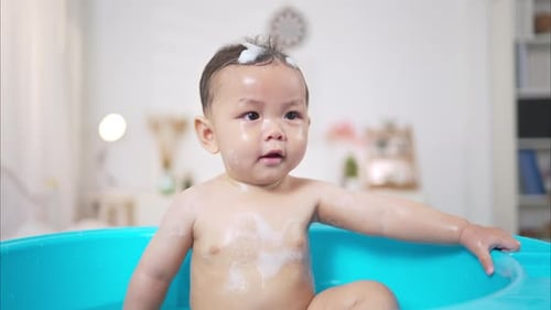 Smiling Infant Enjoys Bath in Turquoise Tub