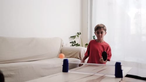 Happy kids playing table tennis or ping pong at home living room - Family lifestyle activities