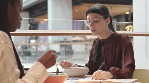 Colleagues Discussing Work during Lunch Break on Food Court