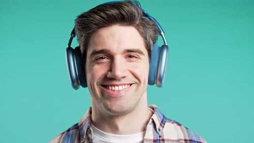 Handsome Positive Man Listening Music Enjoying with Headphones Blue Studio