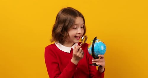 Stylish Smiling School Teenage Girl Holding Magnifying Glass in Her Hand and Look on Globe