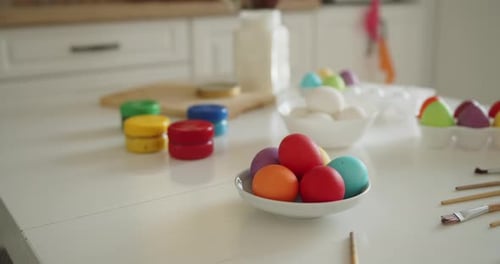 Bunte Ostereier, Farbgläser und Pinsel auf einem Küchentisch