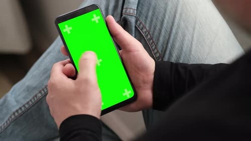 Man Using Smartphone in Vertical Position with Green Mockup Screen Touching