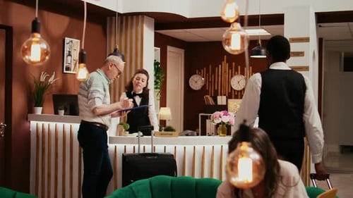 Man Checking Into Hotel Signing Registration Form