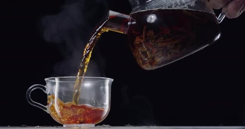 Pouring Tea Into a Clear Glass Mug
