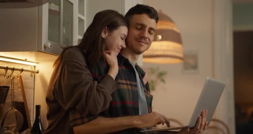 Affectionate Couple Using Laptop Together in Kitchen