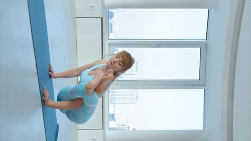 Écran vertical : Jeune femme blonde pratiquant la pose à huit angles ou Astavakrasana