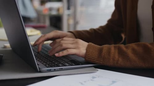 Woman Typing on Laptop in an Office Setting