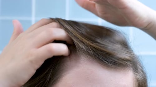 Girl touching her hair close-up on blue background, hair loss concept.