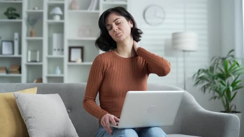 Woman with Neck Pain Using a Laptop at Home