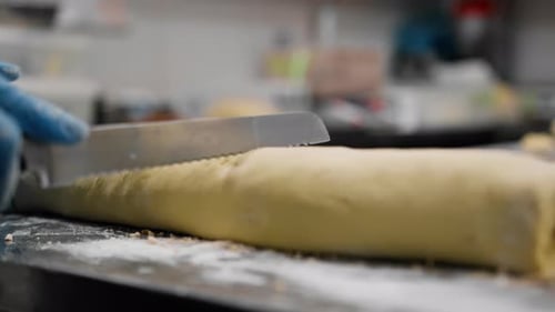 Die Küche in der Bäckerei - der Prozess der Zimtherstellung, die Bäckerin schneidet den Teig