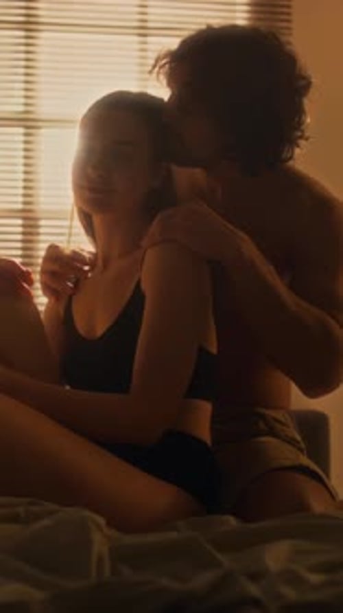 Liebevoller Mann streichelt Freundin auf dem Bett