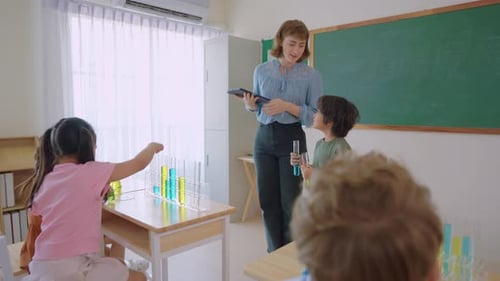 Adorable student learn with teacher in classroom at elementary school.