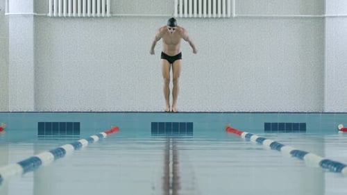 Joven hombre atlético nadador saltando al agua y nada en la piscina Hombre entrenando en el agua