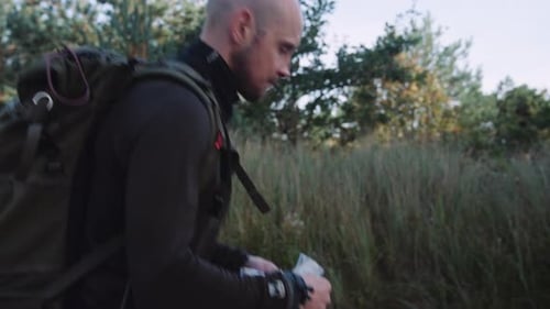 Side View of a Man Tourist with Backpack Hiking in the Forest