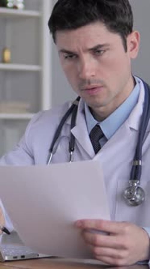 Focused Doctor Reviewing Patient Documents in Office