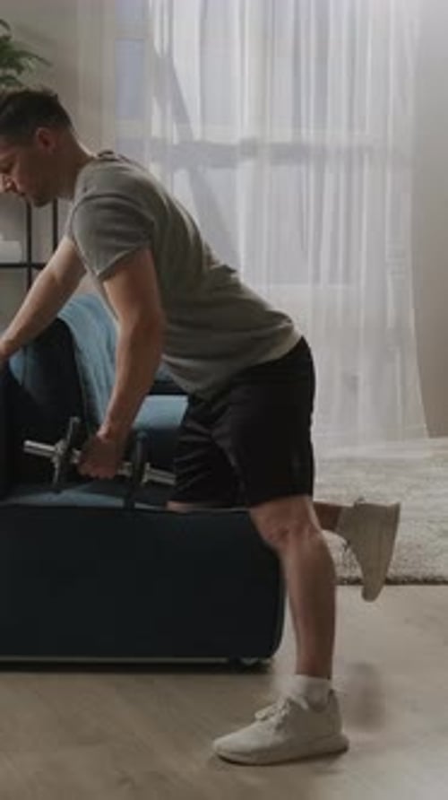 Focused Home Workout Sequence Showing Man Performing Dumbbell Row Exercise Beside Sofa for Strength