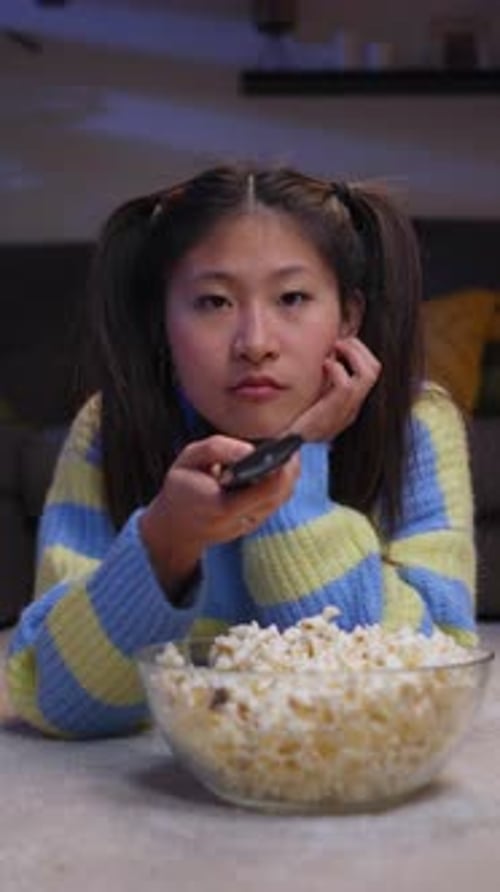 Young Woman Eats Popcorn and Watches Television