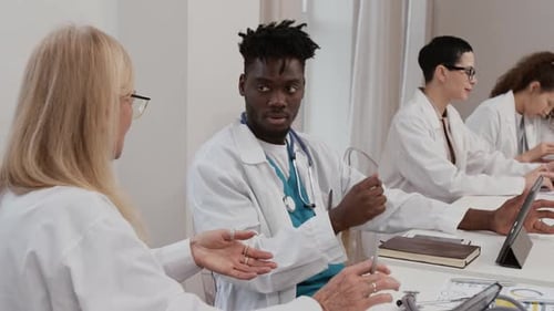 Doctors Meeting and Discussing Patient Data in Workplace