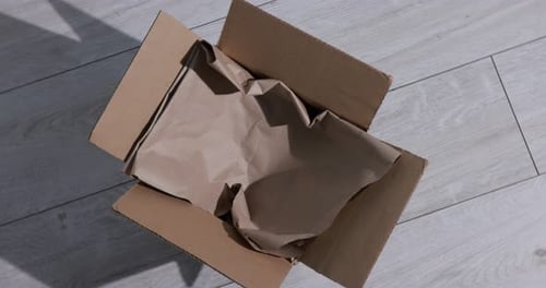 Open empty cardboard box on light wooden surface, spinning