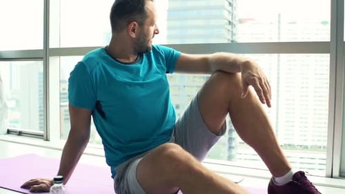 Sporty young man taking a break admiring city view from window at home in slow motion