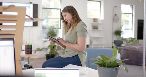 Caucasian casual businesswoman using tablet in office, slow motion