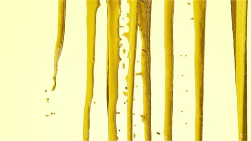 The yellow liquid paint pours unevenly from top to bottom.