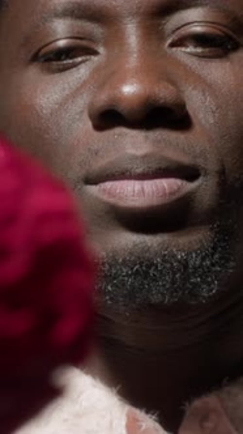 Vertical Close Up of Black Man Putting Flower into Mouth