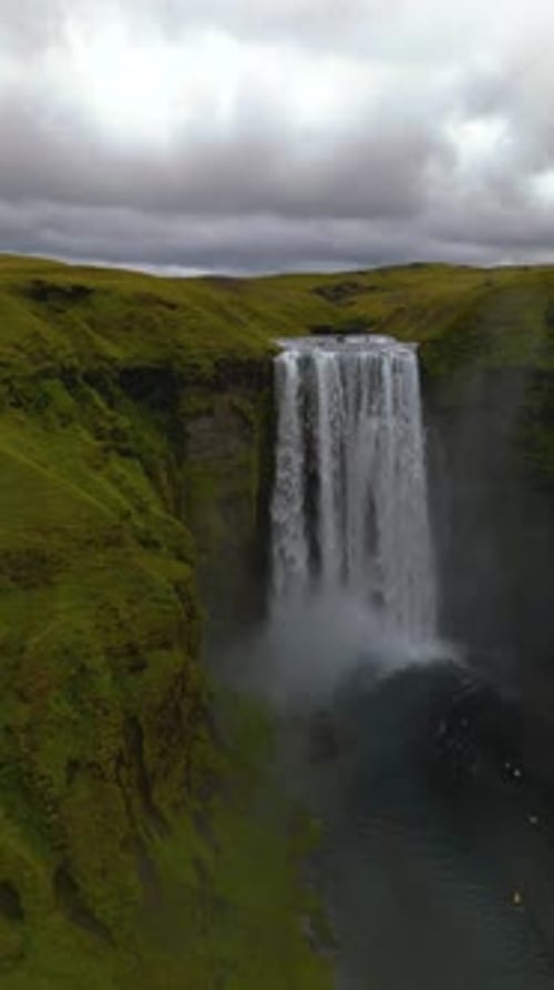 cinematic drone footage of Skógafoss Waterfall in Iceland, capturing the immense curtain of water