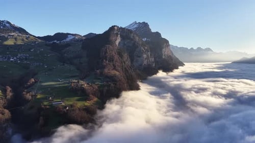 Aerial view of a mountain ridge rising above a sea of clouds, blending nature and rural landscape