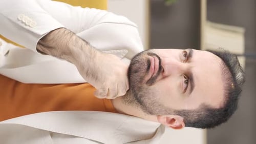 Man Sitting on Couch Itching His Beard