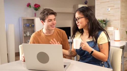 Young Adults Chatting and Using Laptop at Table