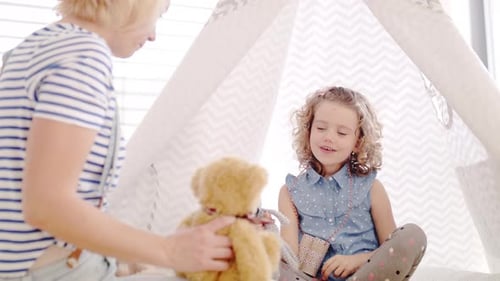 Child playing with blonde woman and teddy bear